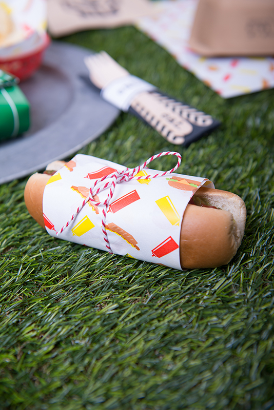 paper wrapped with ketchun mustard and hots dogs printed on it wrapped around a hot dog