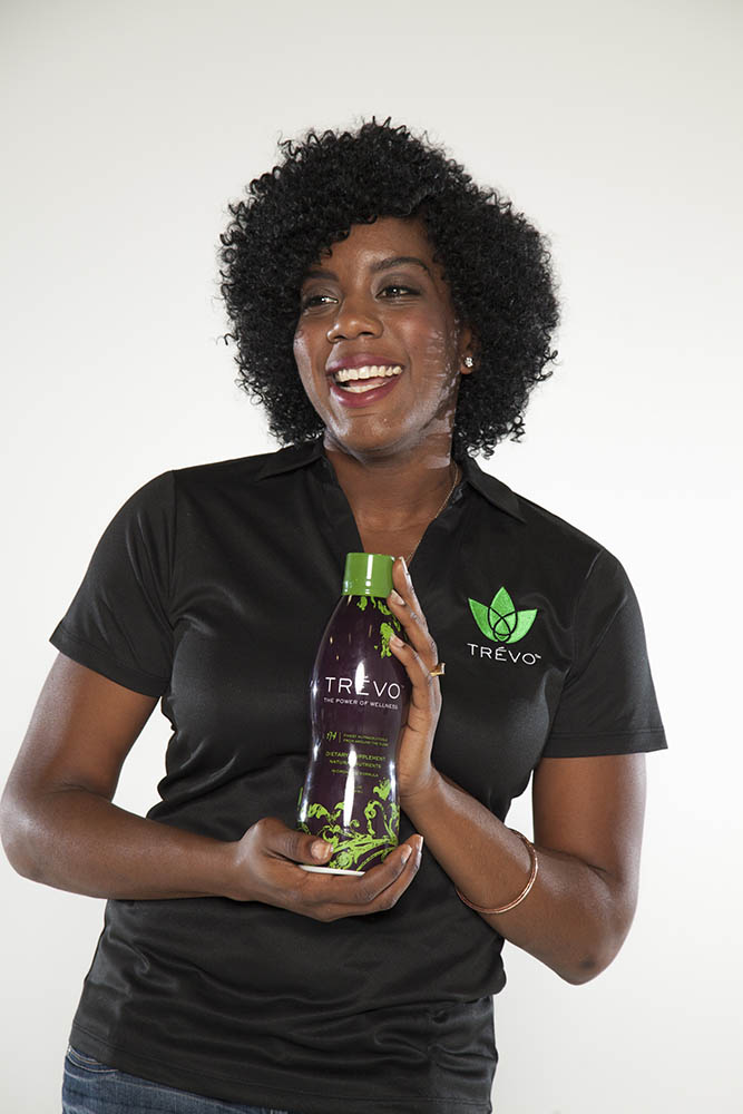 Trévo employee smiling and holding bottle of Trévo