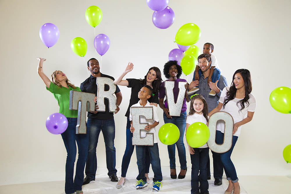 team holding letters that spell Trévo with balloons floating