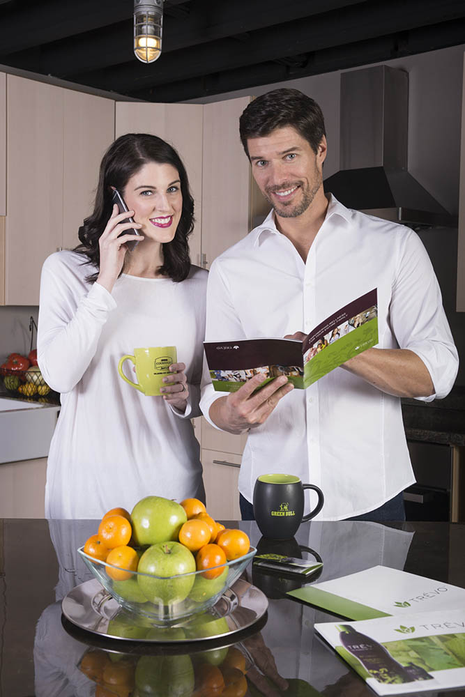 man and woman standing in kitchen reading Trévo brochure