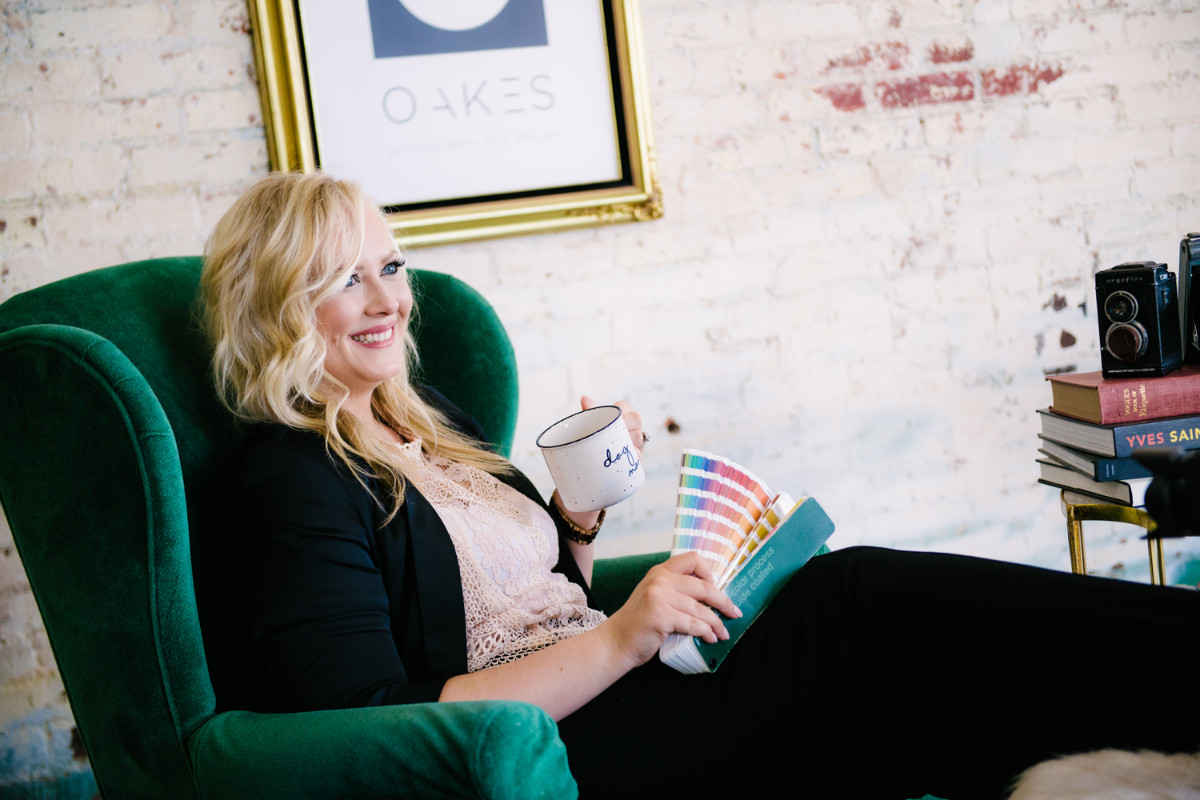 business woman sitting in green chair holding color samples and coffee cup
