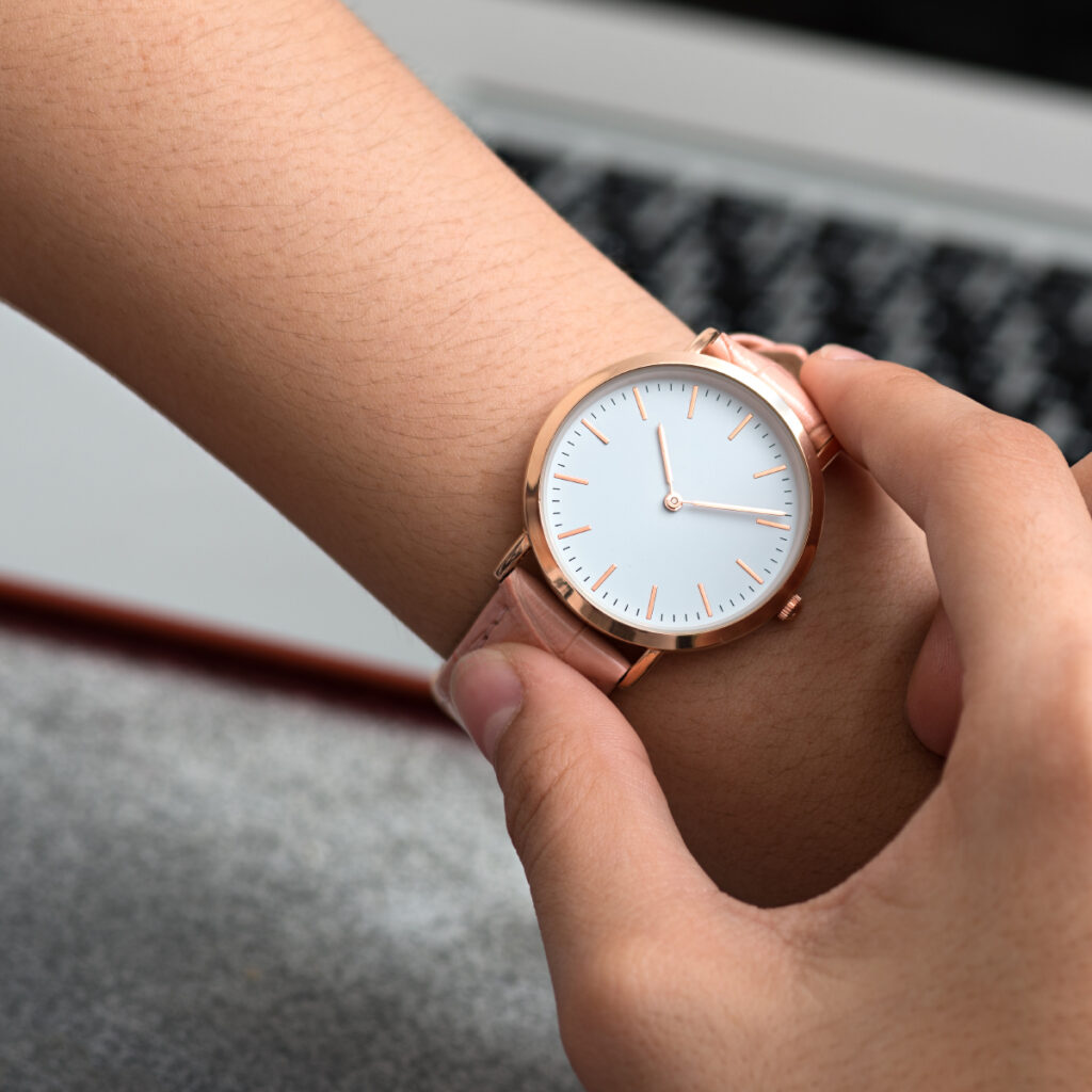A woman's hand, adorned with a stylish watch, confidently showcases it in front of a laptop screen as an example of the perfect business marketing done right.