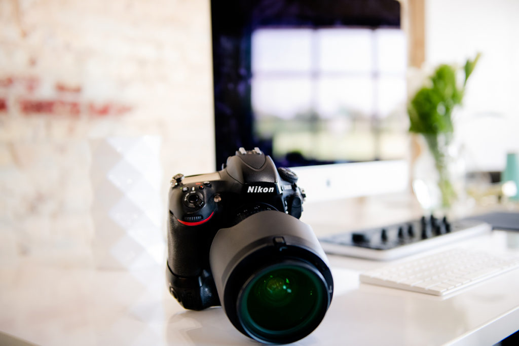 A branding mini shoot captures a DSLR camera placed on a desk with a computer.