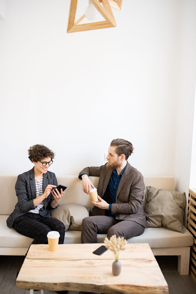 A man and woman sitting on a couch while discussing business marketing tips.