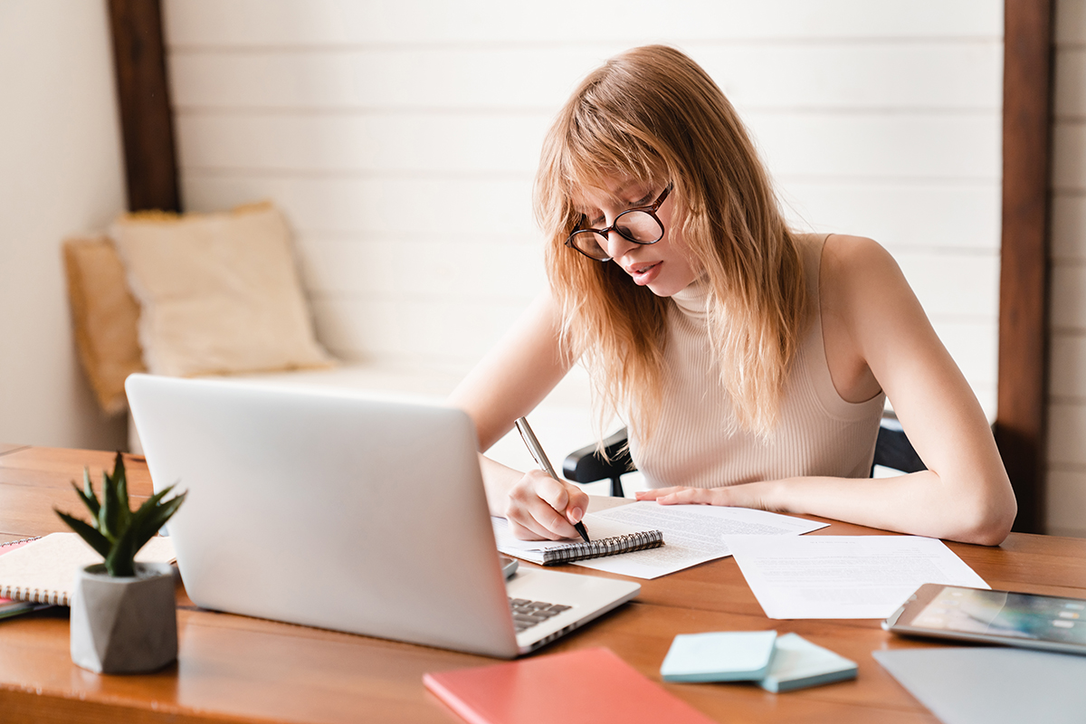 E-learning, webinars, college homework concept. Businesswoman tutor freelancer making notes using laptop remotely on part-time job