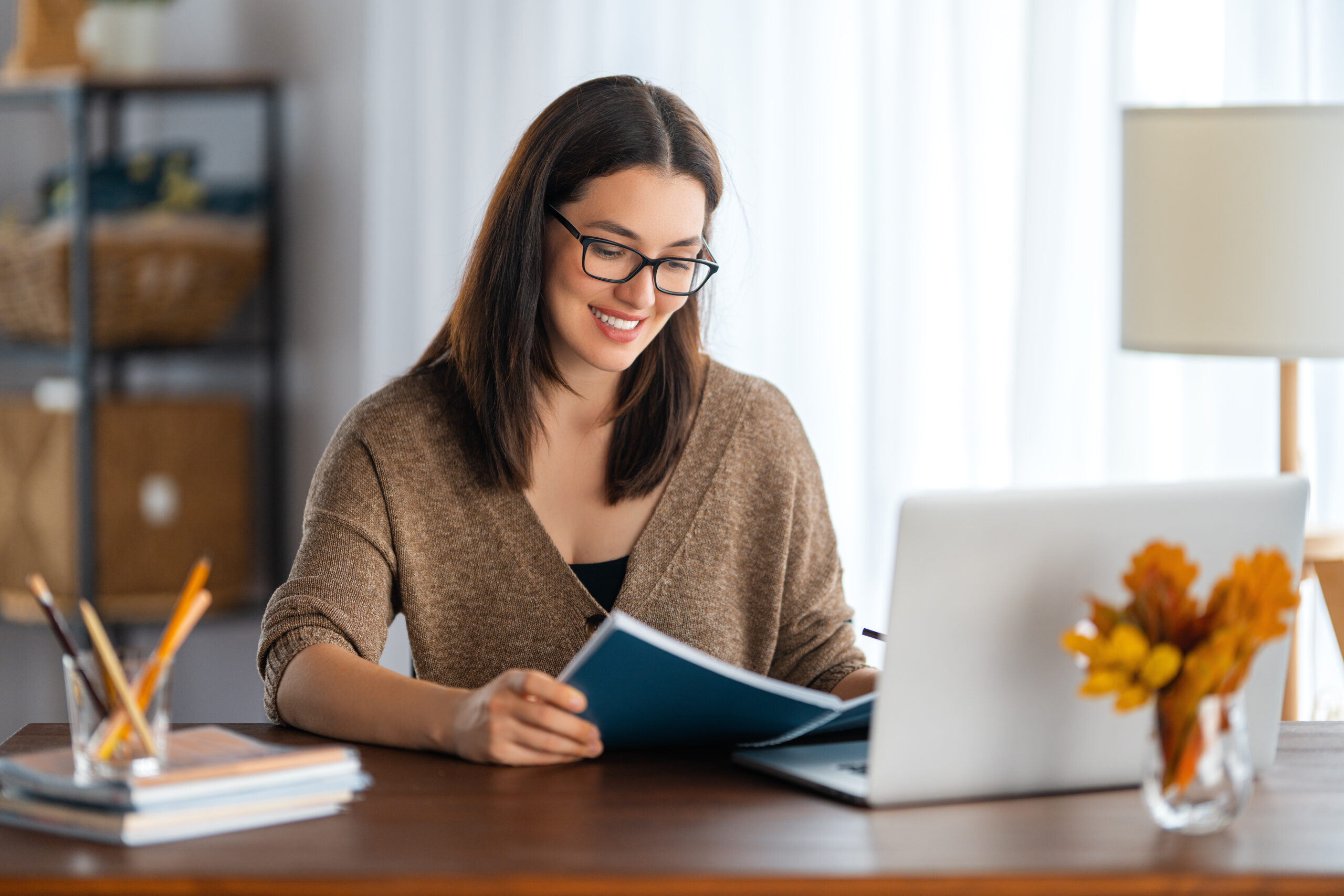 young woman working at desk smiling looking down at paper planner