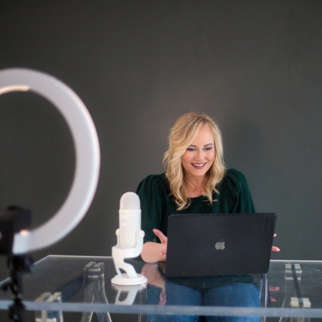 A woman sitting at a desk with a laptop and a ring light for education purposes.