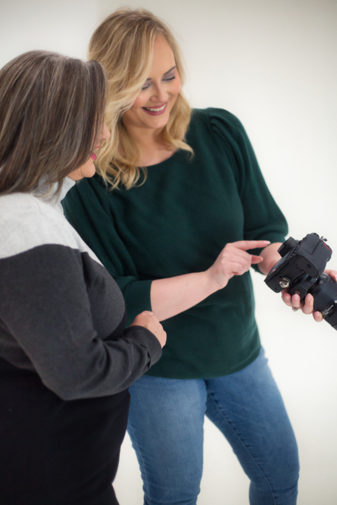 Two women reviewing photos on a digital camera together for corporate branding purposes.