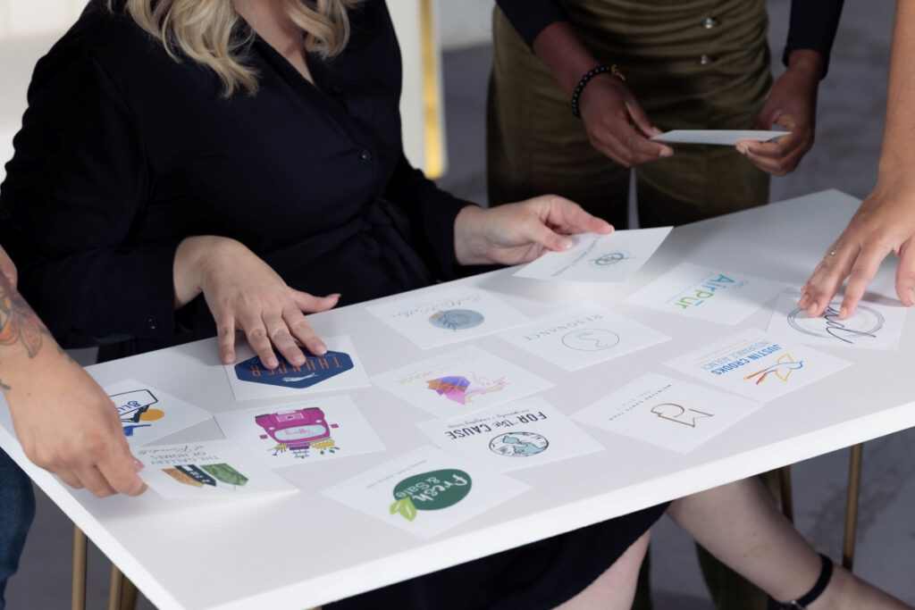 Team collaborating on design trends by reviewing logo concepts and branding ideas laid out on a table.