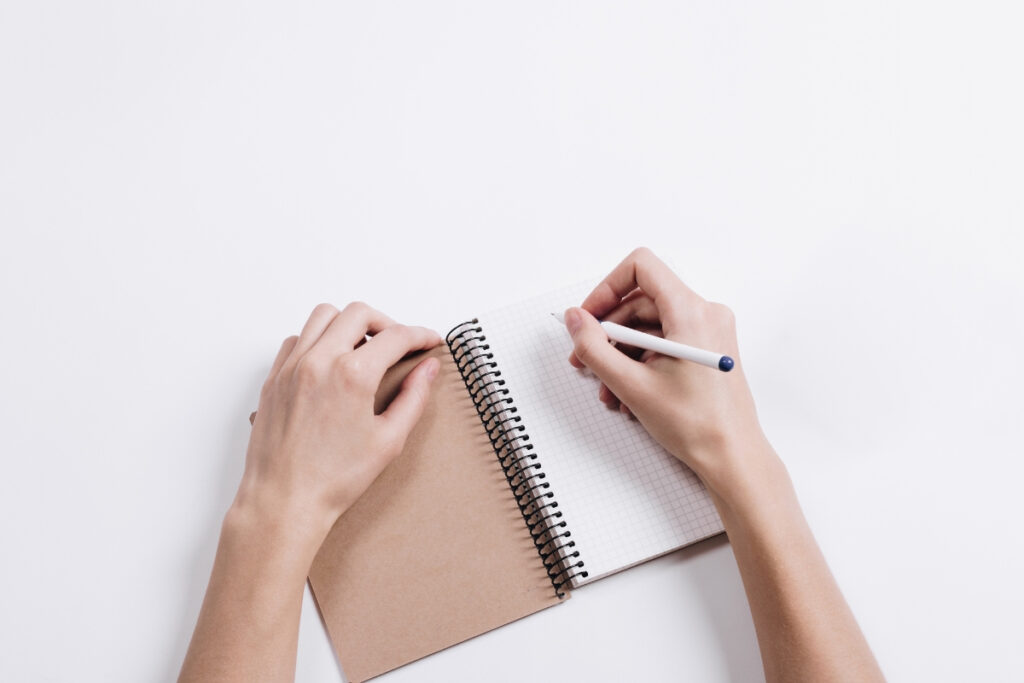 Notebook and hands writing, symbolizing content-driven design as 2025 brand trends.