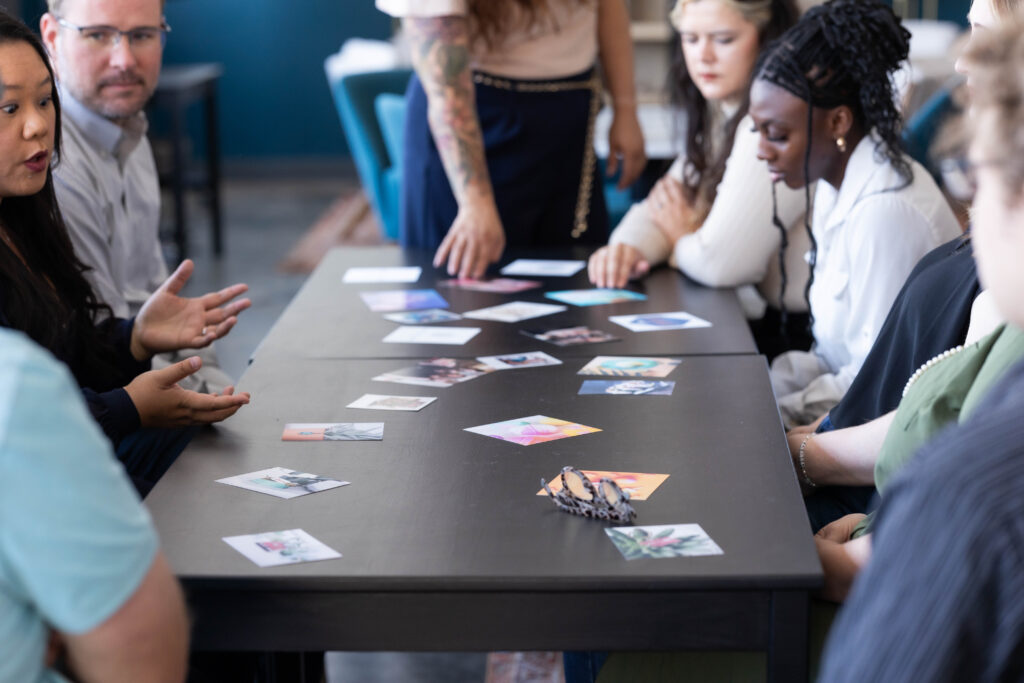 Group gathered around a table sorting through strategy cards during a discussion on identifying and avoiding marketing mistakes.