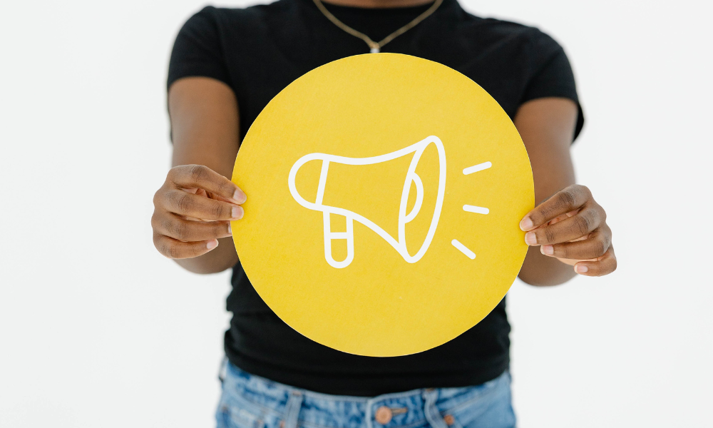 A creative agency team member holds a bright yellow sign with a megaphone icon.