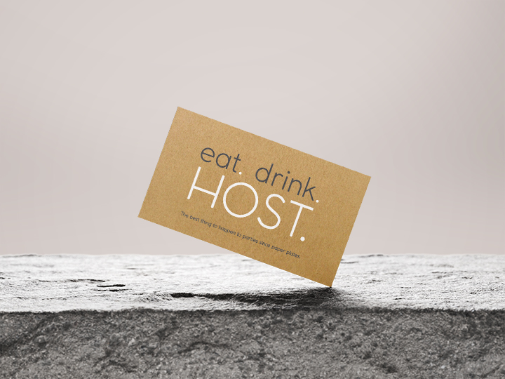 Eat Drink Host branded business card displayed on a textured stone surface with minimalist neutral background.